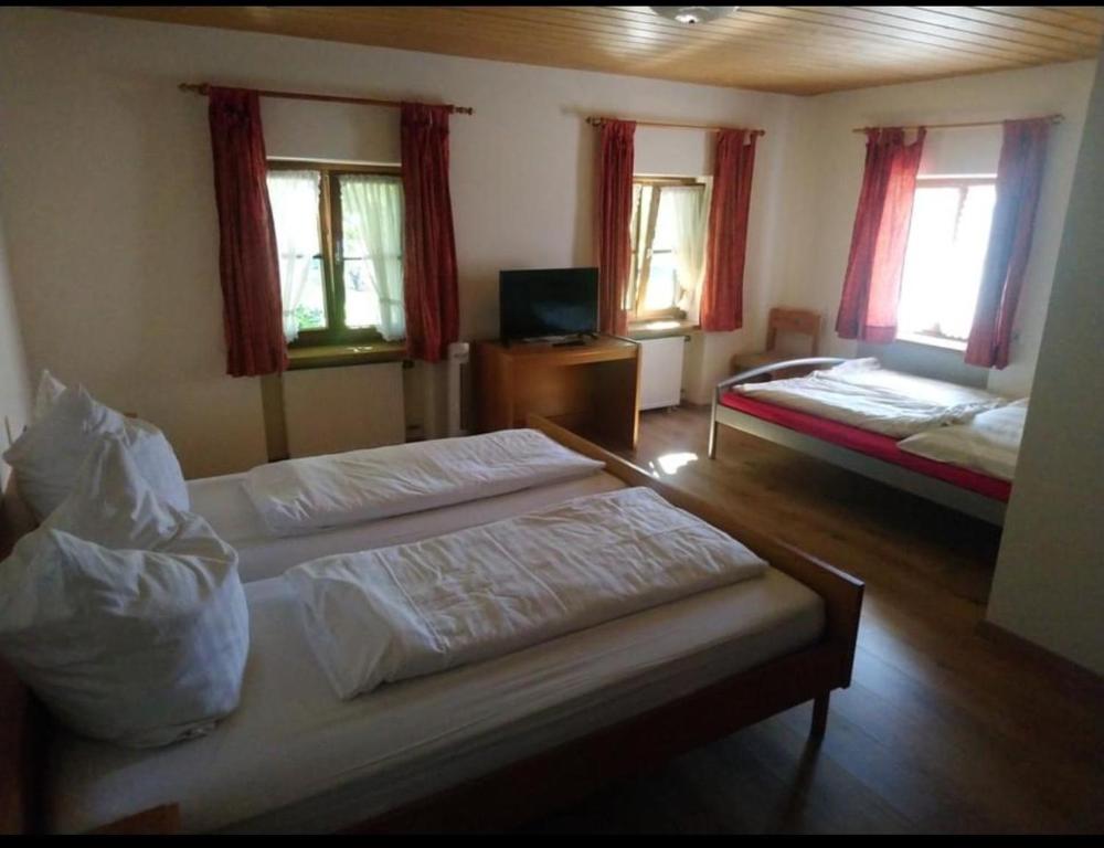 a bedroom with two beds and a tv and windows at Gasthof Mühlegger in Wildsteig