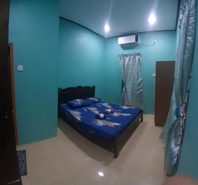 um quarto com uma cama com uma parede azul em Beijing View Homestay em Rantau Panjang