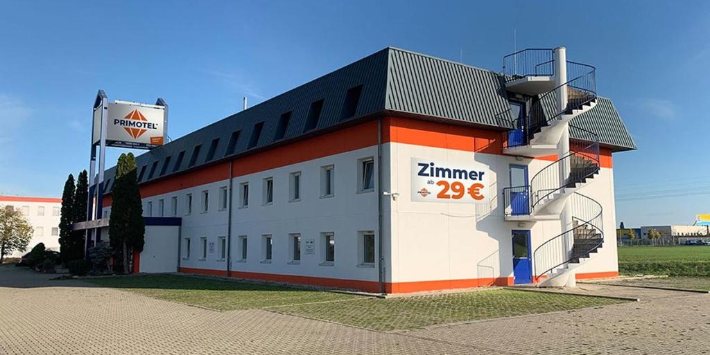 Biały i pomarańczowy budynek z napisem w obiekcie PRIMOTEL w mieście Schkeuditz