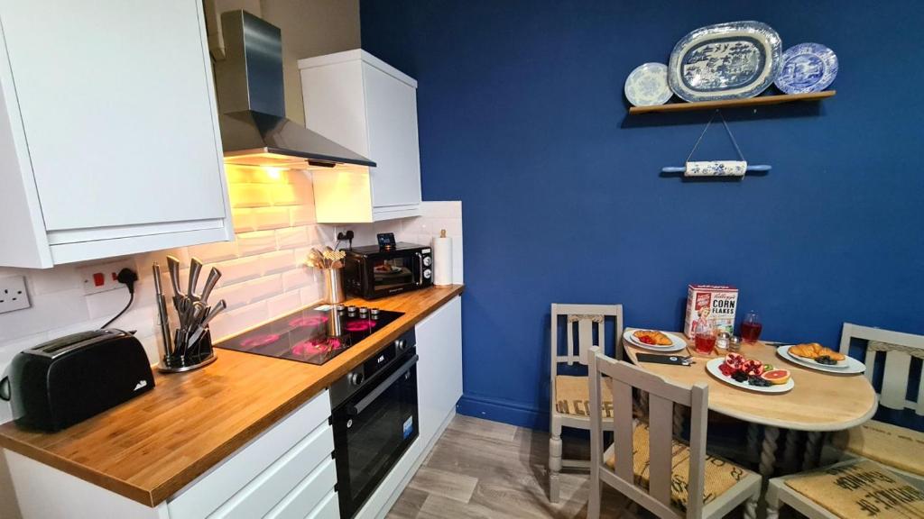 a small kitchen with a small table and a blue wall at Potter's Place at Newcastle under Lyme, Close to Keele University in Longport