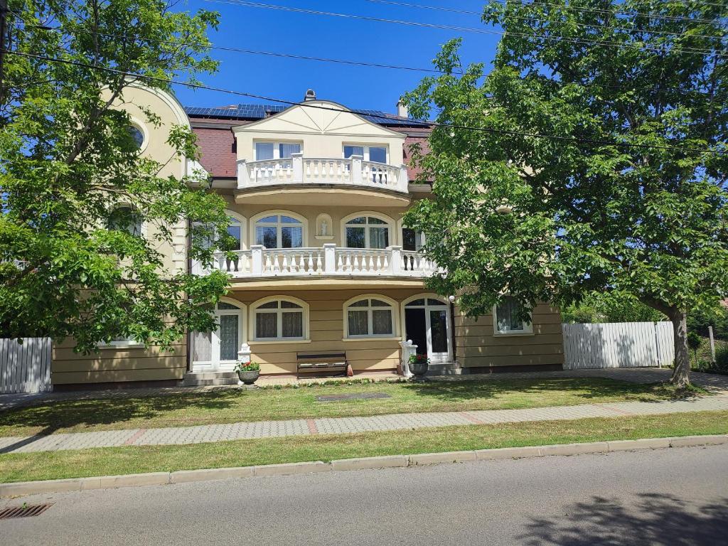 Una gran casa amarilla con un balcón en la parte superior. en Pelso Apartments, en Siófok