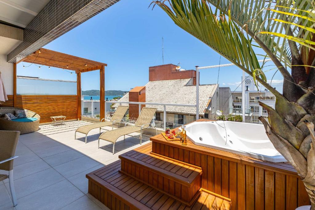 a bath tub sitting on the deck of a house at Cobertura Vista Mar, Jacuzzi Privada e Área Gourmet - Praia de Mariscal - 3 dorm até 10 pessoas in Bombinhas