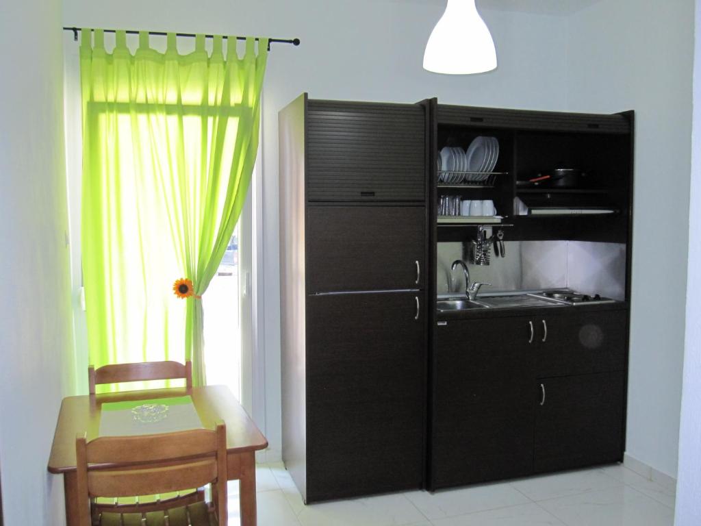 メタモルフォシにあるMetamorfosis Apartmentsのキッチン(黒いキャビネット、テーブル、シンク付)