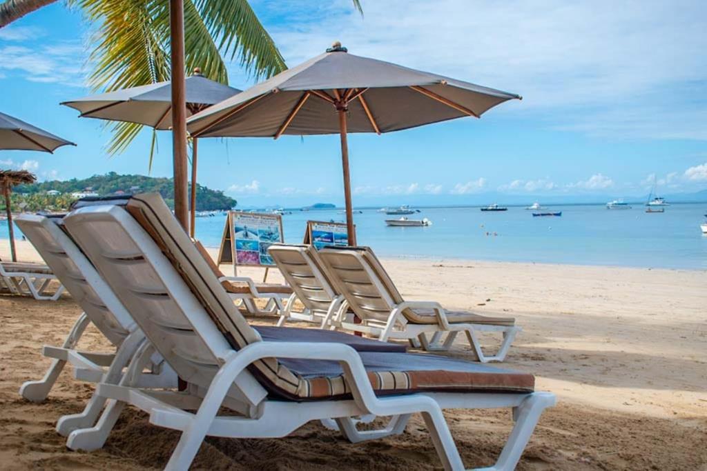 een groep stoelen en parasols op een strand bij Hotel-Residence Au Sable Blanc in Madirokely