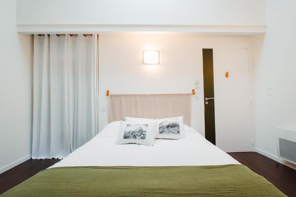 a bedroom with a large white bed with two pillows at Chalets et gîtes d'Orlu in Orlu