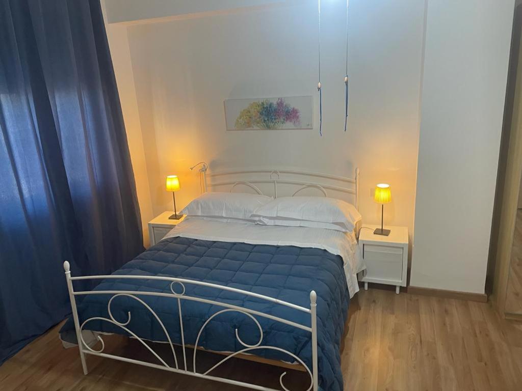 um quarto com uma cama com lençóis azuis e 2 candeeiros em OLEANDRI SUITE B&B em Aprilia