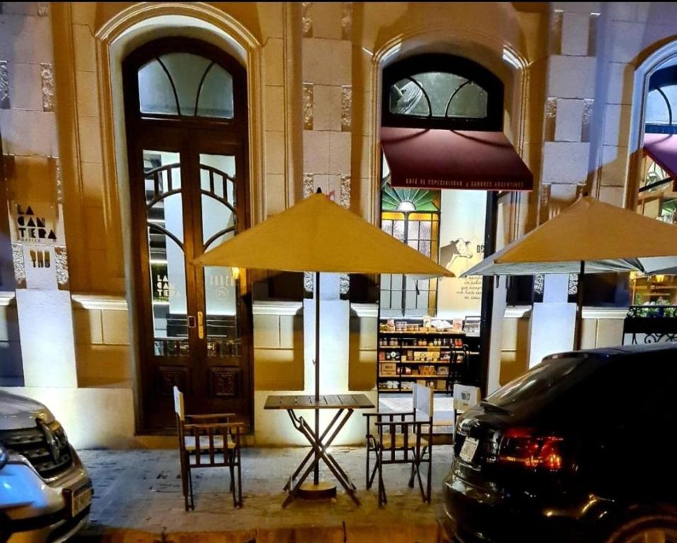 un tavolo e sedie sotto ombrelloni in un edificio di ANDÉN FMA-Coliving a Salta