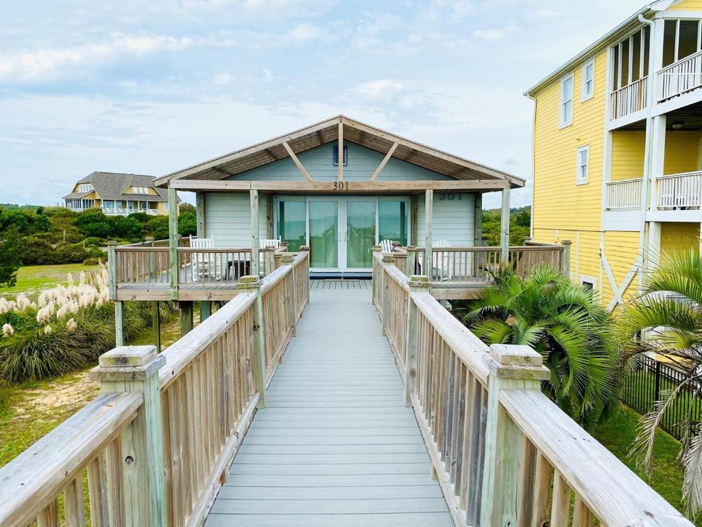 a wooden bridge leading to a house with a yellow at Serenity Now in Holden Beach