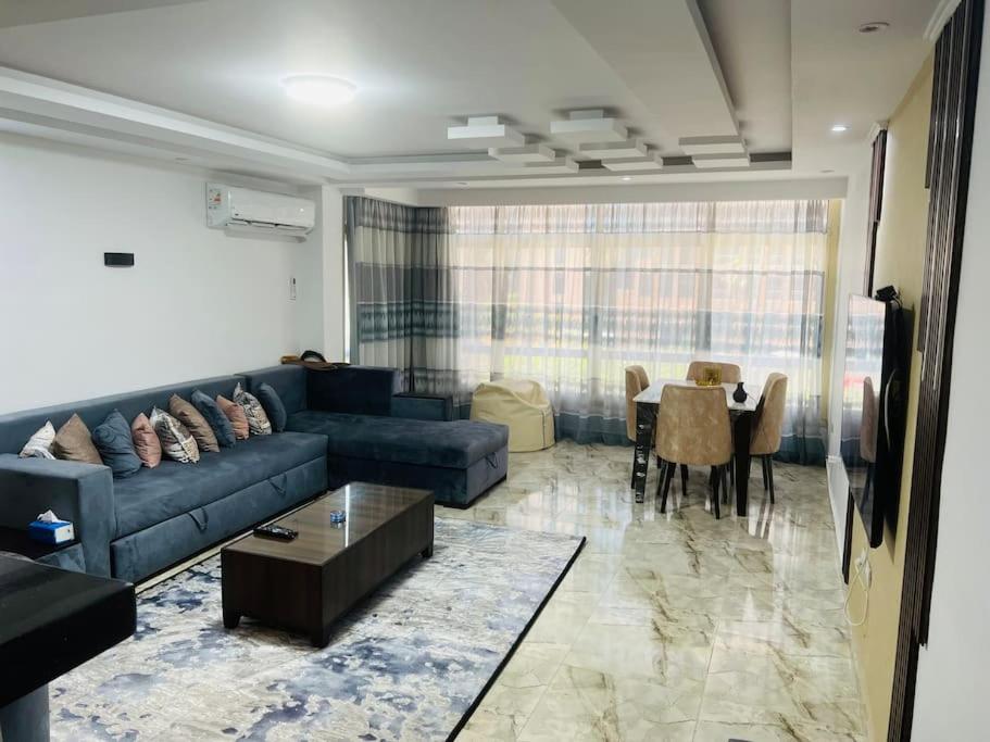 - un salon avec un canapé bleu et une table dans l'établissement Amazing Apartment Overlooking CityStars, au Caire
