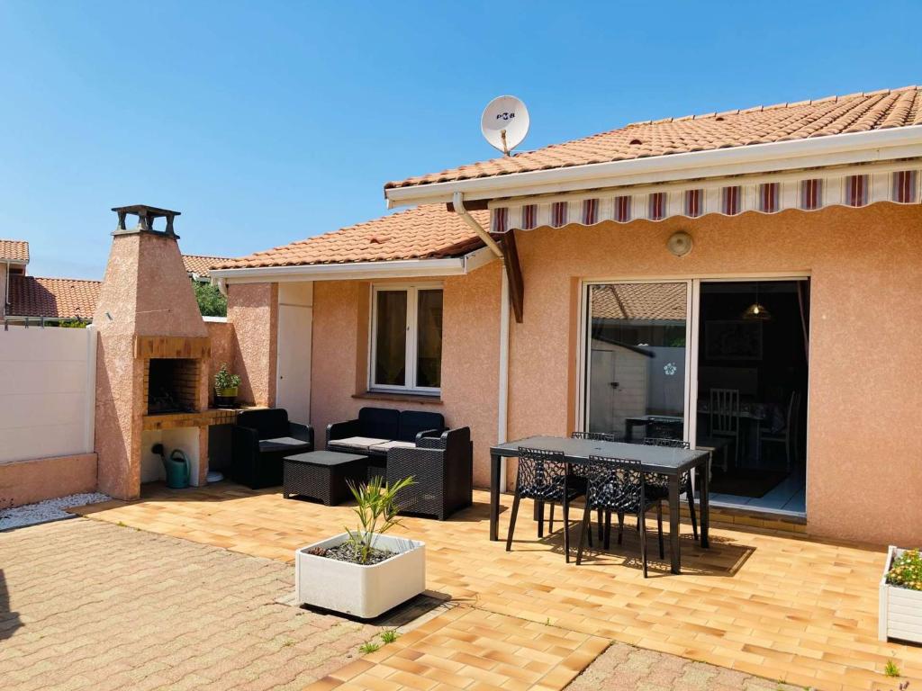 un patio d'une maison avec une table et des chaises dans l'établissement Biscarrosse Duplex classé 2 étoiles avec parking privatif pour 6 personnes, à Biscarrosse