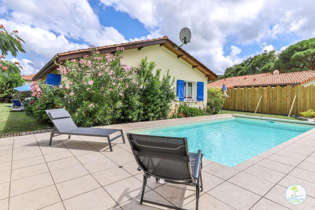 eine Terrasse mit 2 Stühlen und einem Pool in der Unterkunft Biscarrosse Bourg Villa 8 personnes avec piscine in Biscarrosse