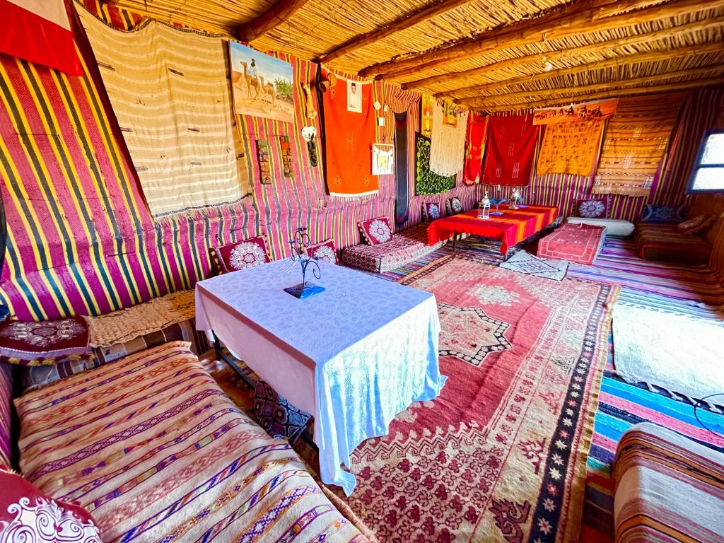 Mhamid Sahara Golden Dunes Camp - Chant Du Sable في Mhamid: غرفة مع طاولة وكراسي في غرفة