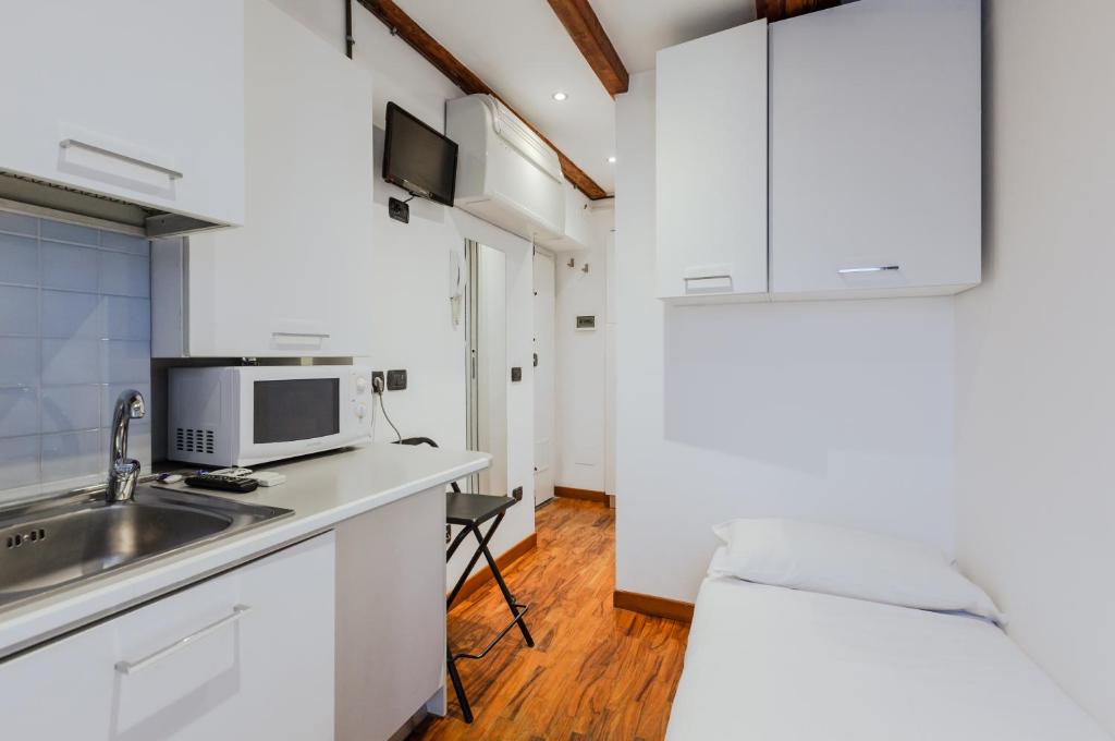 ミラノにあるSant Ambrogio Lovely Flatの白いキャビネットとシンク付きのキッチン