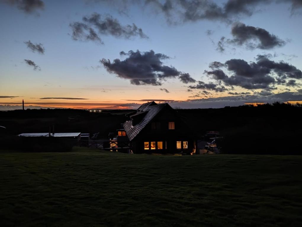 une maison dans un champ avec le coucher du soleil en arrière-plan dans l'établissement Anglesey Outdoors, à Holyhead