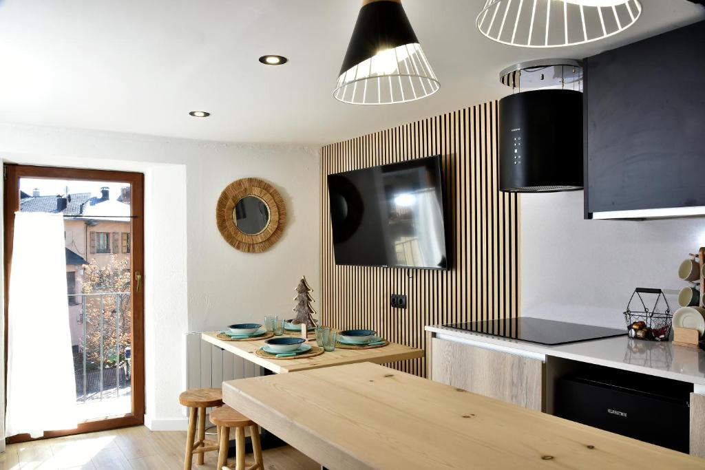 cocina con mesa de madera y TV en la pared en LA CASETA DELS HEROIS, en Puigcerdà