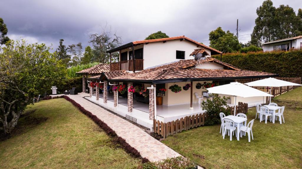ein Haus mit einer Veranda sowie Tischen und Stühlen in der Unterkunft Finca Villa Isanella, Santuario, Antioquia in Santuario