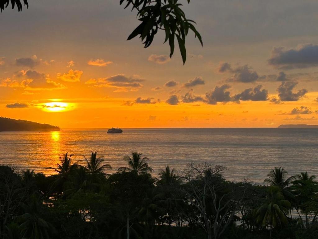 einen Sonnenuntergang über dem Meer mit einem Boot im Wasser in der Unterkunft Natural Drake Bay Hotel Boutique in Drake