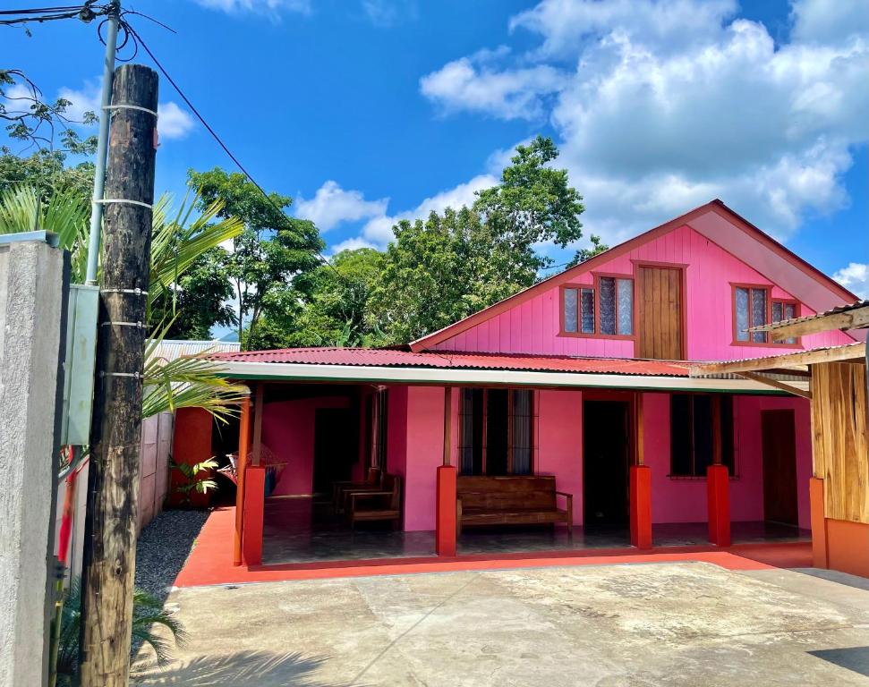 una casa rosa con un banco delante en Casa Nativo Spring Arenal, en Fortuna