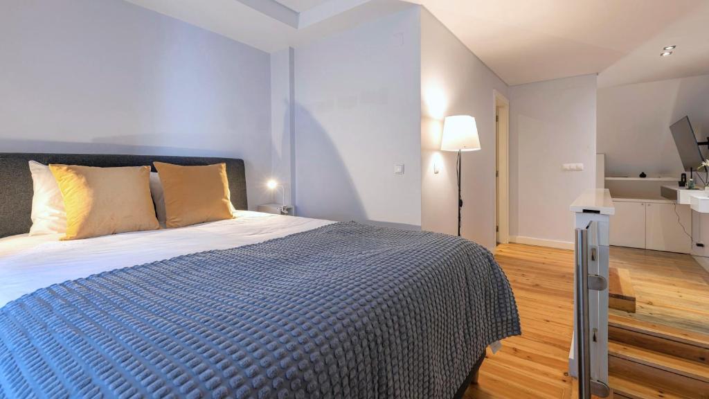 1 dormitorio con 1 cama grande y edredón azul en Lisbon Fancy Duplex W/ Patio by LovelyStay, en Lisboa
