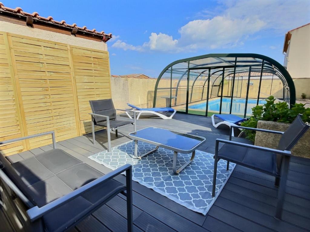 um deque com cadeiras, uma mesa e uma piscina em Villa avec piscine à 10 min des plages. em Vendres