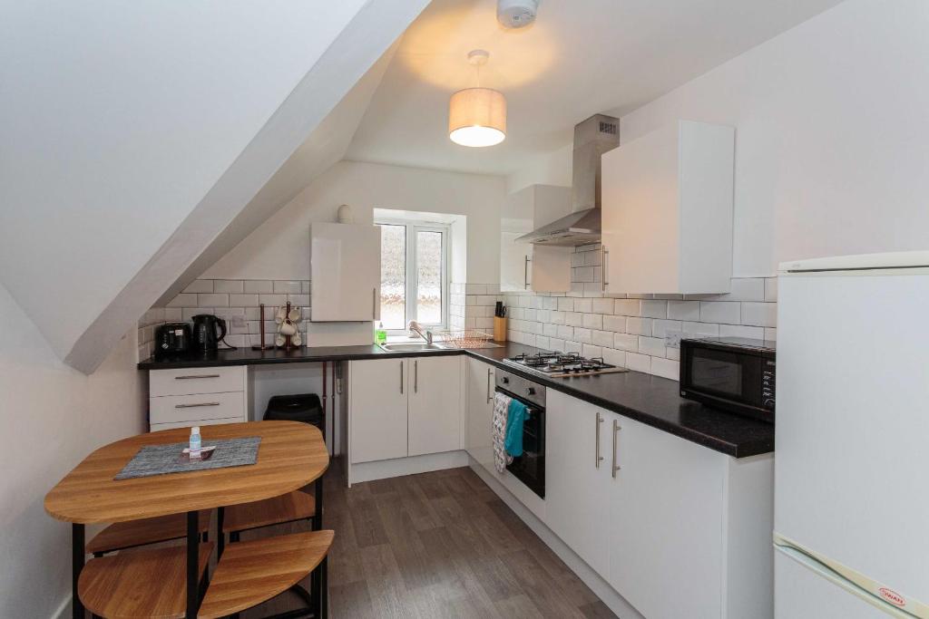 a kitchen with white cabinets and a wooden table at Cherry Property - Blueberry Suite in Blackpool