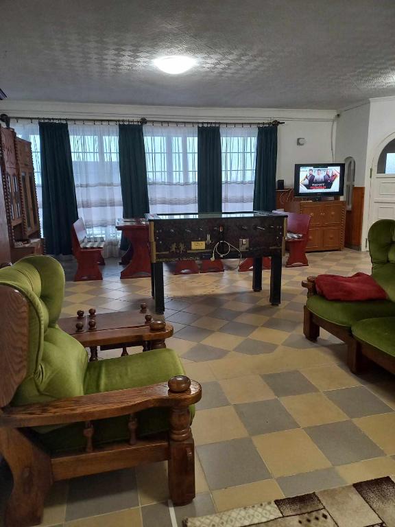 salon z pianinem i zielonymi krzesłami w obiekcie Evita Vendégház w mieście Sajókápolna