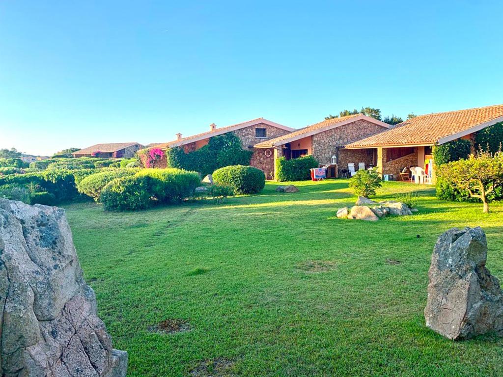 a yard with a stone wall in front of a house at Cala Paradiso Apartment "Casa Agave" - SeaView, Wifi, AC in San Teodoro