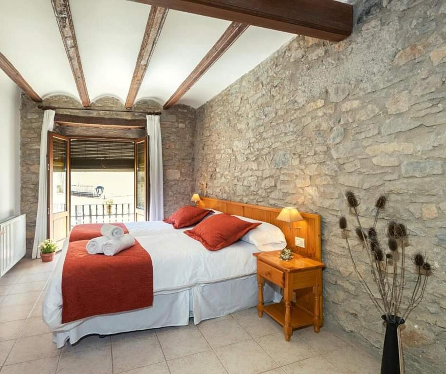 a bedroom with a bed and a stone wall at Hotel D` Ares in Ares del Maestre