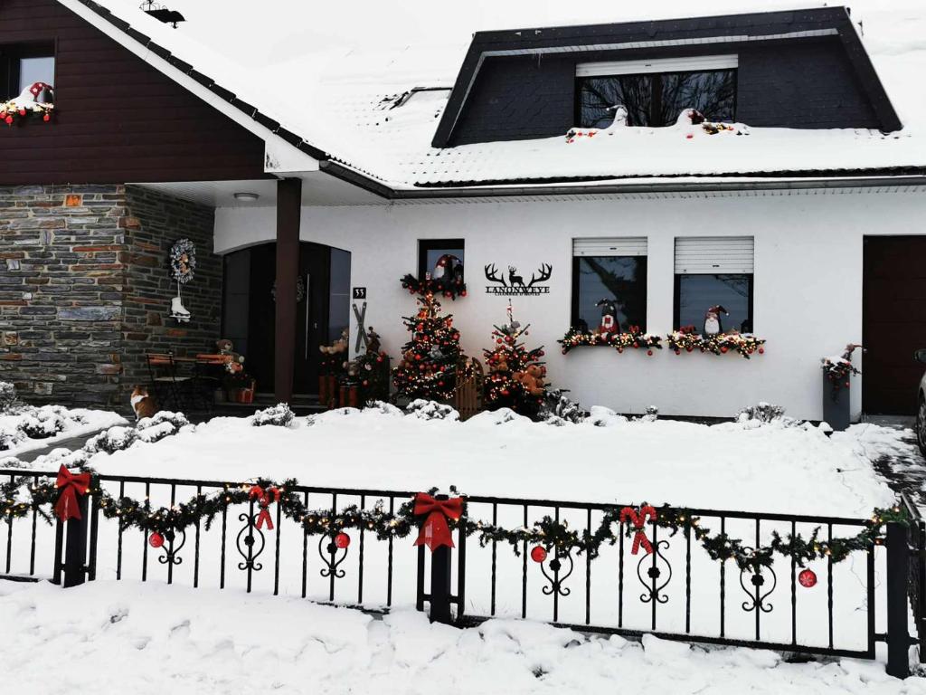 a house with a fence with christmas wreaths in the snow at Lanonweye in Waimes