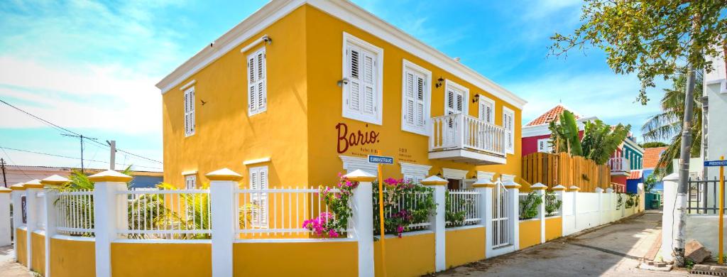 a yellow building with a white fence in front of it at Bario Hotel in Willemstad