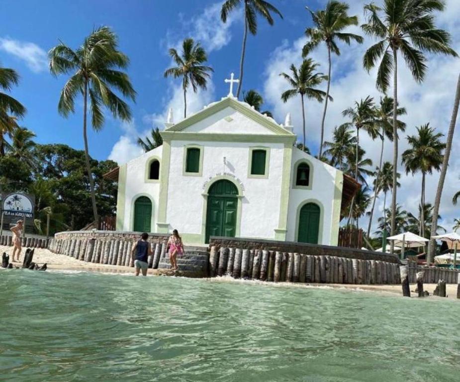 une église sur la plage avec des gens debout dans l'eau dans l'établissement Reserva dos Carneiros 301, à Tamandaré