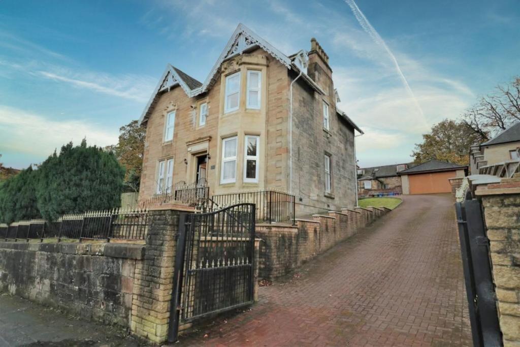 an old house on a stone wall with a gate at 10 Bedrooms Pool Table Garden Piano in Glasgow