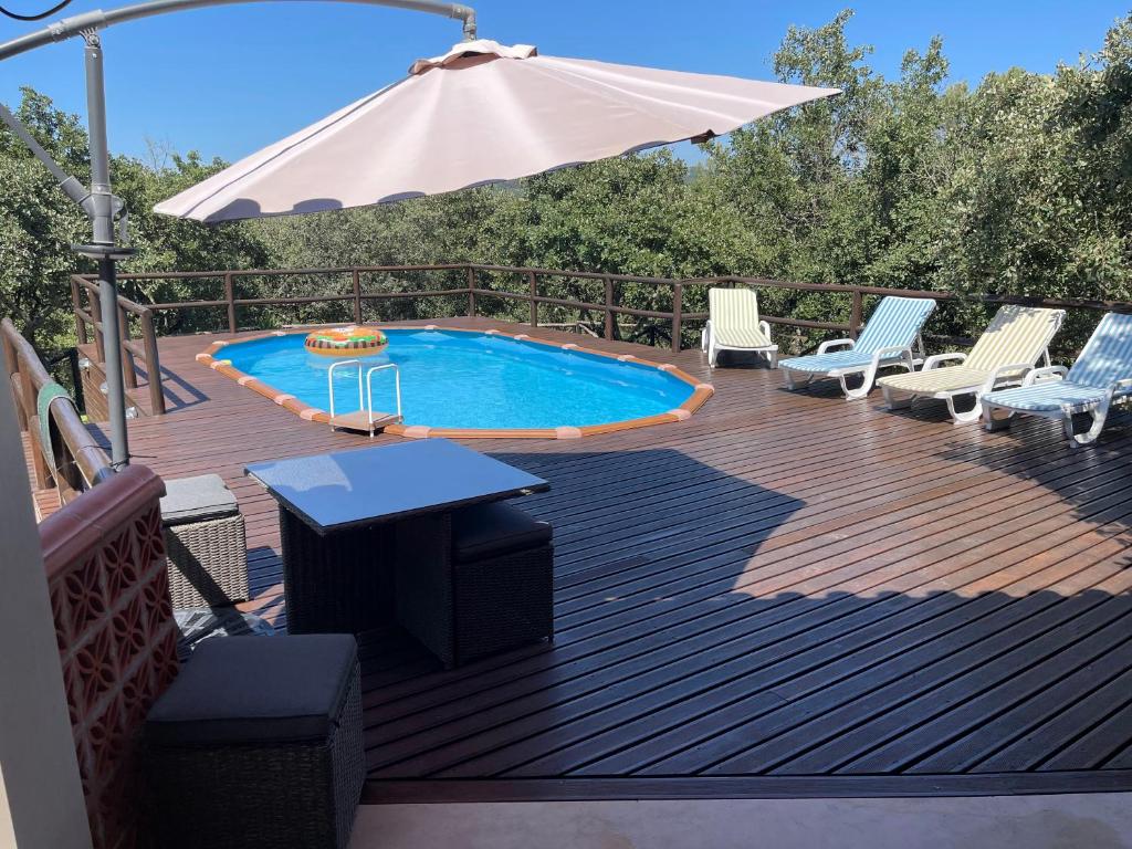 a deck with a swimming pool and an umbrella at Quintinha da Bé, Ourém, Portugal in Ourém