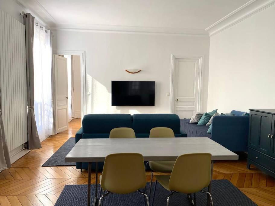 un salon avec un canapé, une table et des chaises dans l'établissement Mytripinparis - Large and Sunbathed 1Br - close to the Eiffel Tower, à Paris