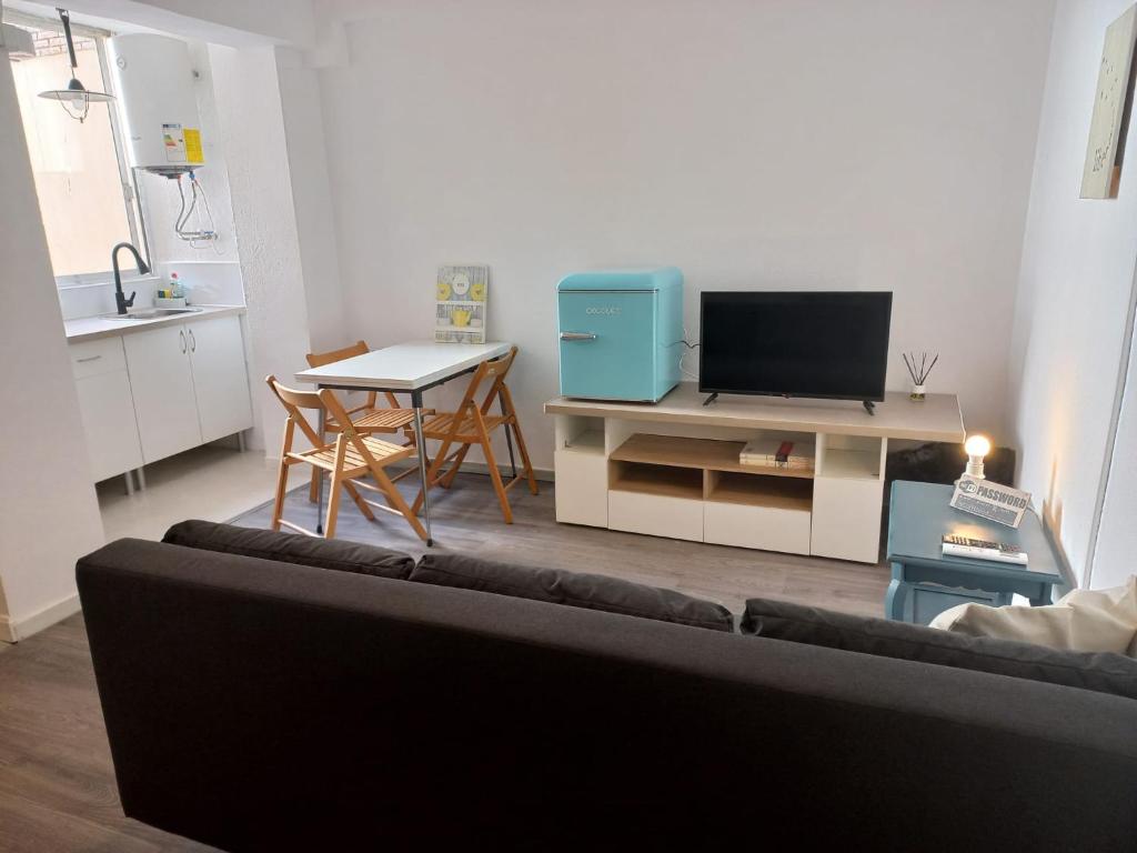 a living room with a couch and a table with a television at Apartamentos céntricos a 10 min de la playa in Almería