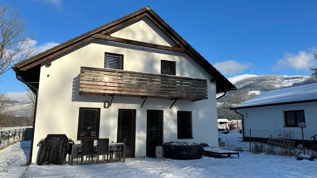 una vieja casa blanca en la nieve con montañas en Apartmánový dom Žiar s vírivkou a saunou, en Žiar