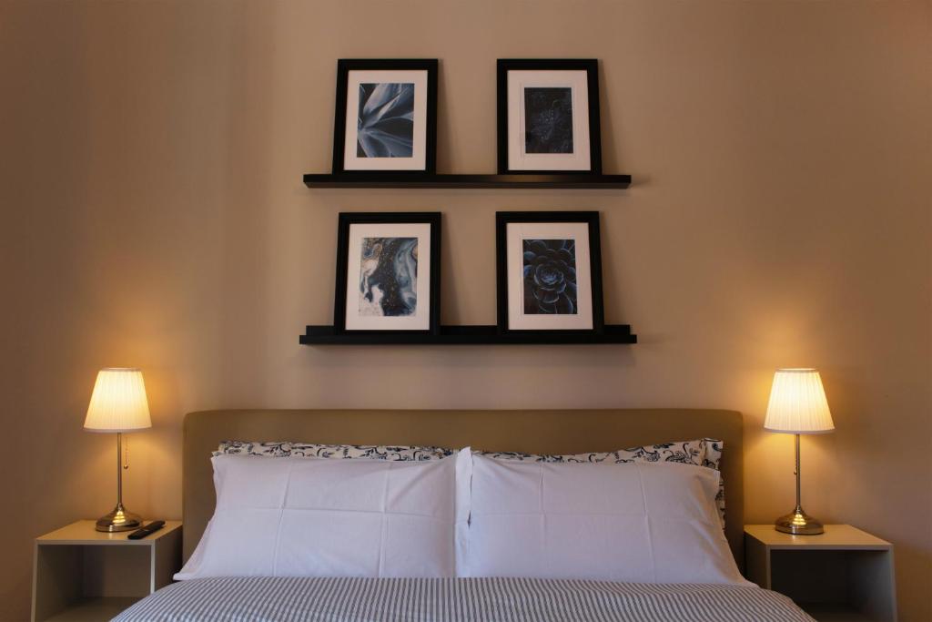 een slaapkamer met een bed met drie foto's aan de muur bij Domus Oriana in Rome
