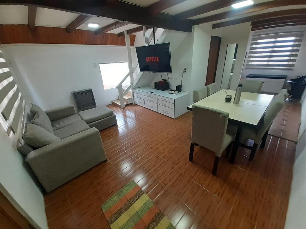 sala de estar con mesa, sofá y TV en alpina el libertador en Ushuaia