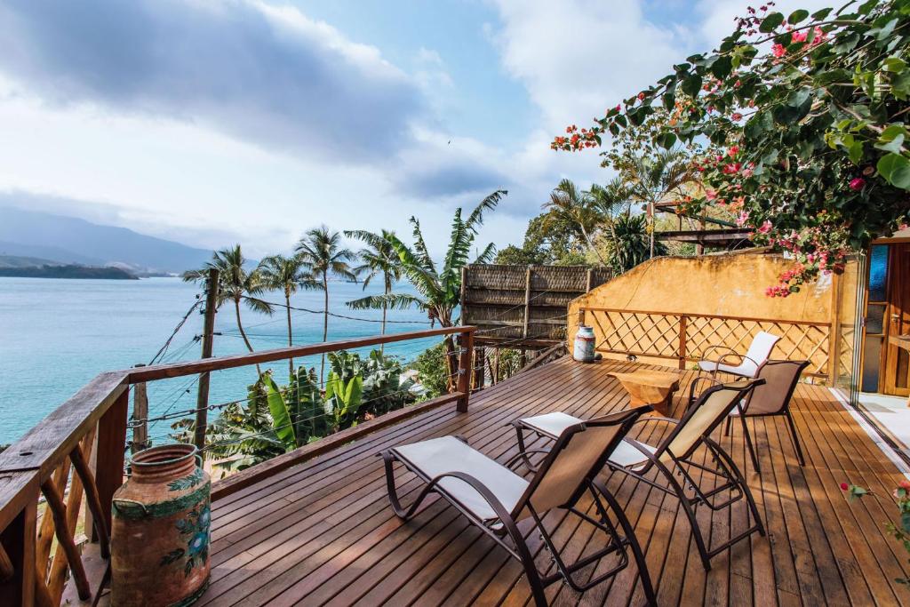 um deque com cadeiras e uma mesa e o oceano em Refúgio na natureza com vista espetacular em Ilhabela em Ilhabela