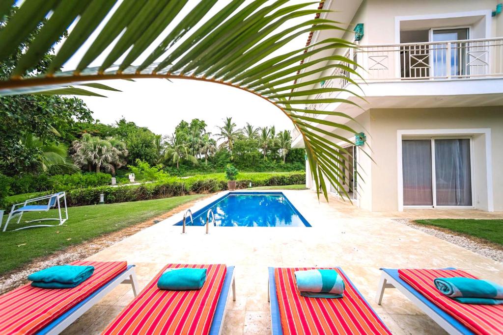 Villa con piscina con sillas rojas y azules en Private Iberosta Villa Lagoon 4BDR- Private Beach and Pool, en Punta Cana