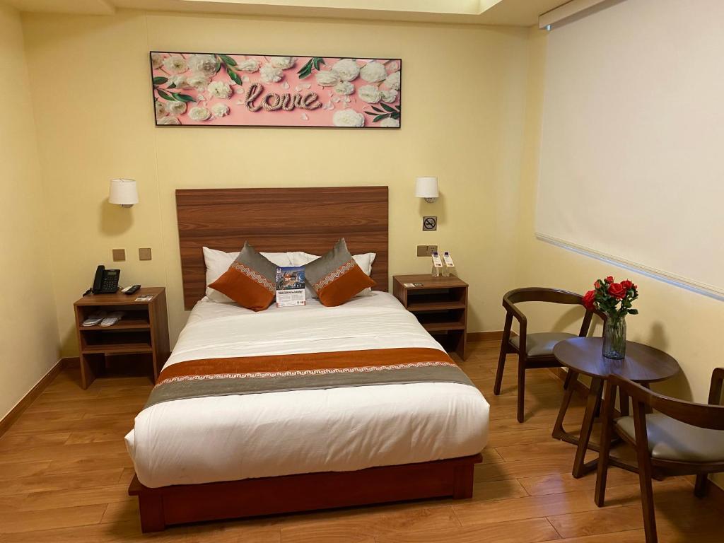 Un dormitorio con una cama y una mesa con un jarrón de flores en SM HOTEL Plus en Lima