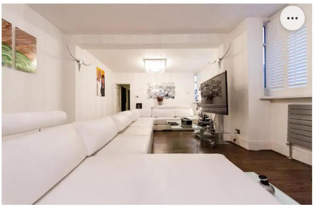 a white living room with a large white couch at Super large apartment in London for larger groups in London