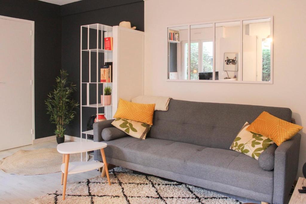 uma sala de estar com um sofá cinzento e almofadas amarelas em Cozy 40 m in Old Puteaux em Puteaux