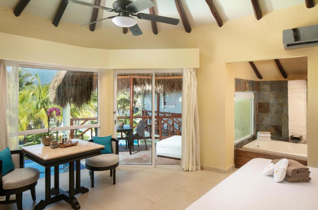 a bedroom with a bed and a desk and a bathroom at El Dorado Casitas Royale Catamarán, Cenote & More Inclusive in Puerto Morelos