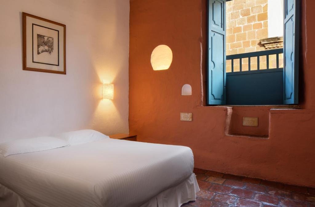 a bedroom with a white bed and a window at Posada del Campanario in Barichara