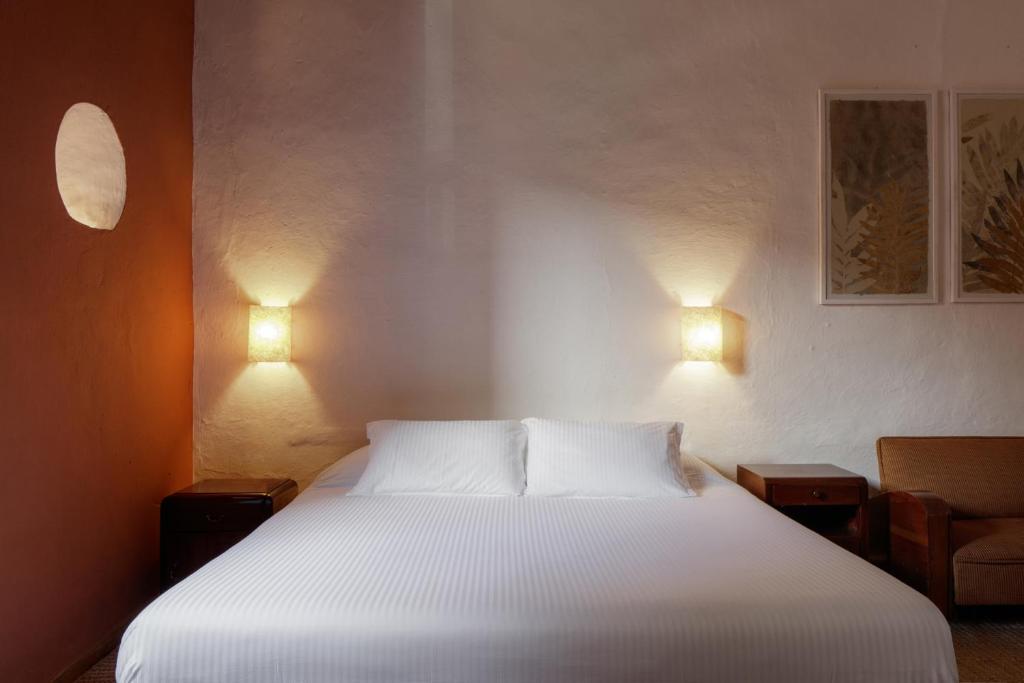 a bedroom with a white bed with two lamps at Posada del Campanario in Barichara