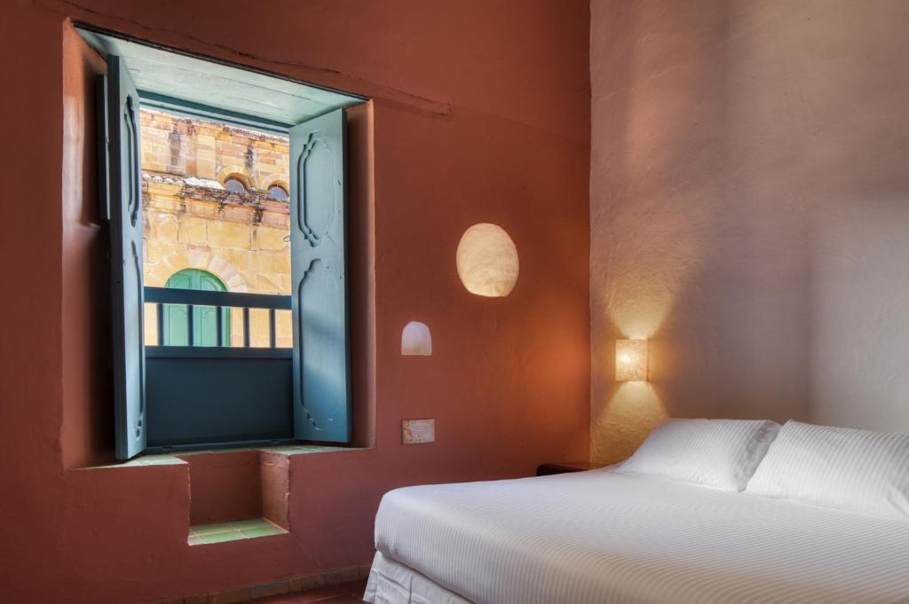 a bedroom with a bed and a window at Posada del Campanario in Barichara
