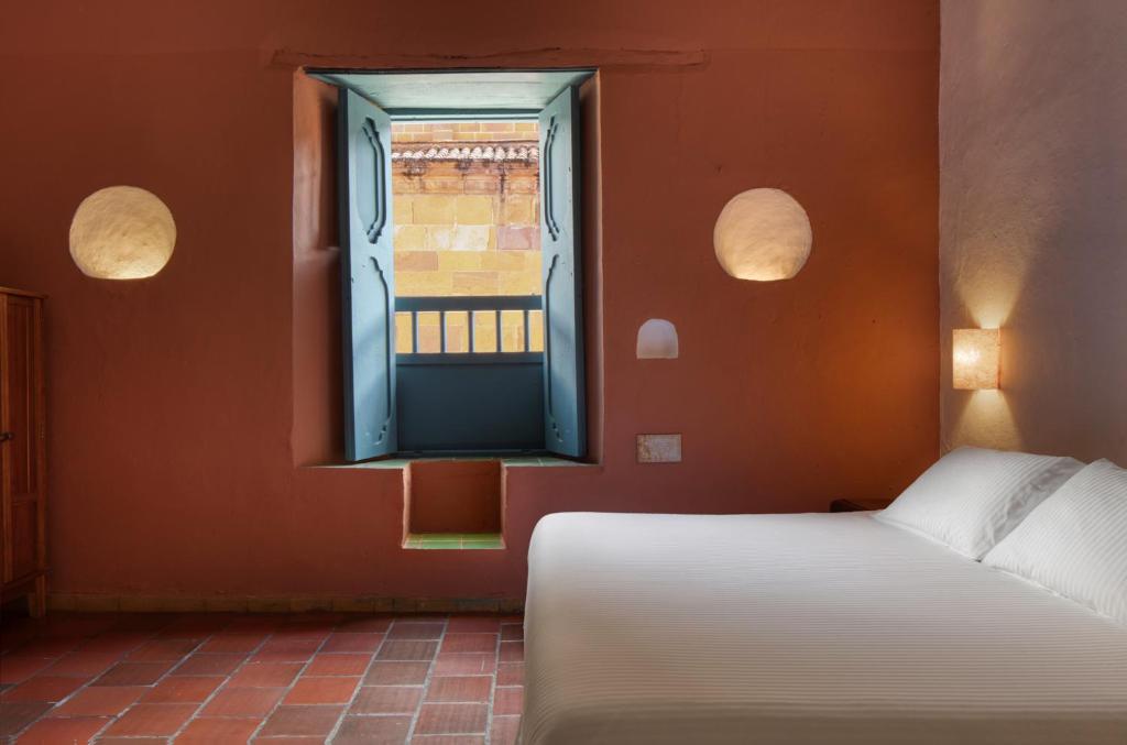 a bedroom with a white bed and a window at Posada del Campanario in Barichara