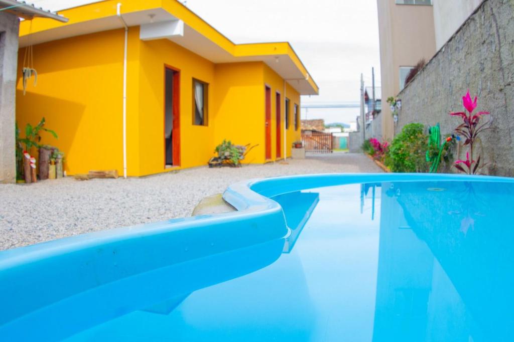 a swimming pool in front of a yellow house at Apartamento encantador próximo praia mercado Farm padaria in Imbituba