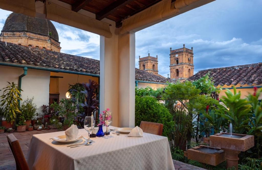 a table in a courtyard with a castle in the background at Posada del Campanario in Barichara